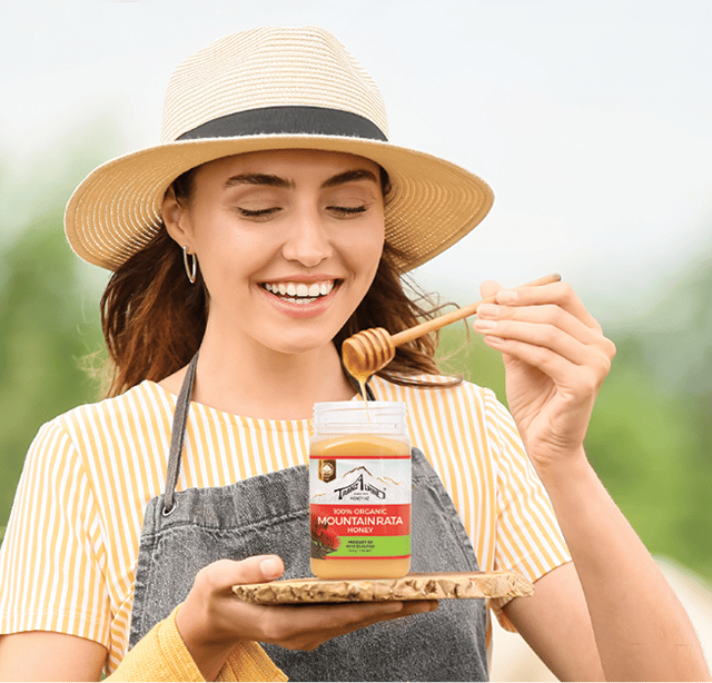 Woman with hat holding jar of TranzAlpineHoney Rata Honey